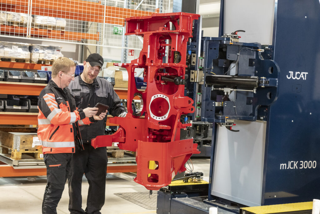 Kuvassa Outokummun Metallin kokoonpanoasentaja ja tuotantopäällikkö seisovat harvesteripään vieressä tarkastelemassa tuotanto-ohjetta.