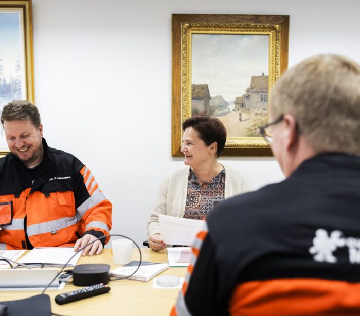 Kuvassa on kolme henkilöä pöydän ääressä yrityksen neuvotteluhuoneessa